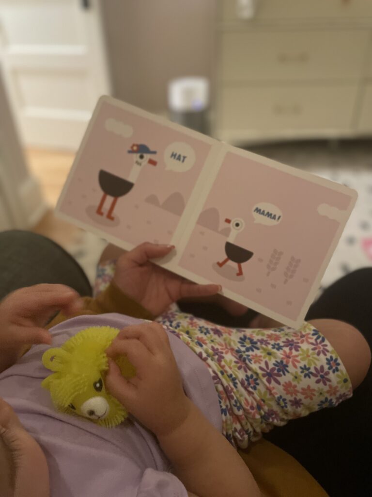 Nina gently holding an infant while reading a book